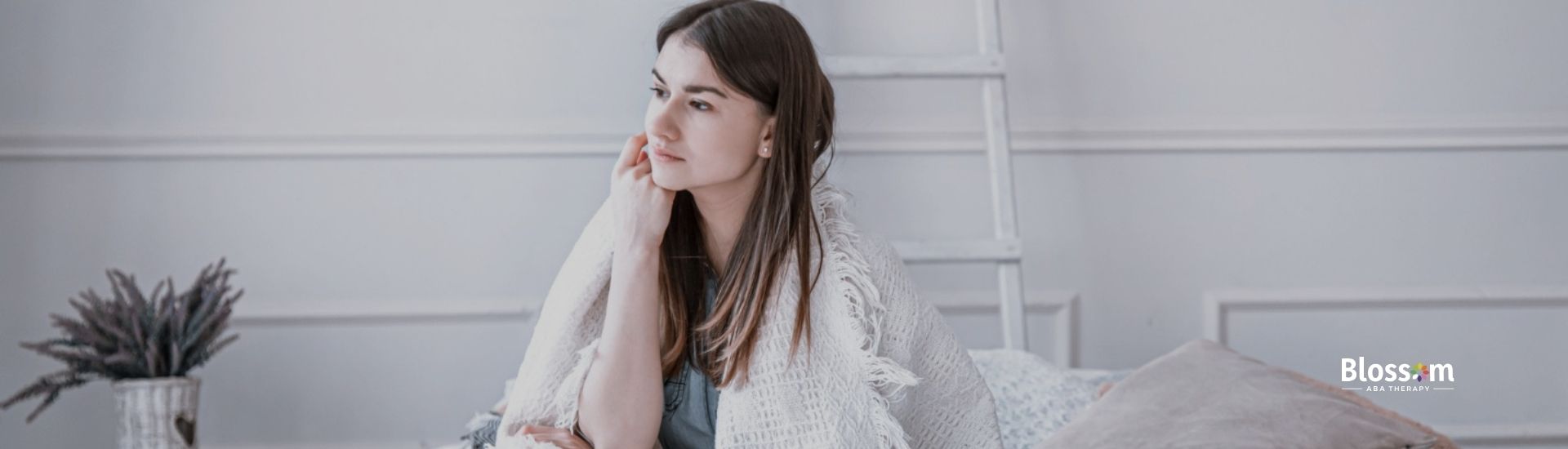 Thoughtful woman with autism wrapped in a blanket.