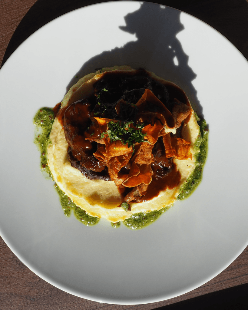 a glass of cocktail with a slime orange fruit