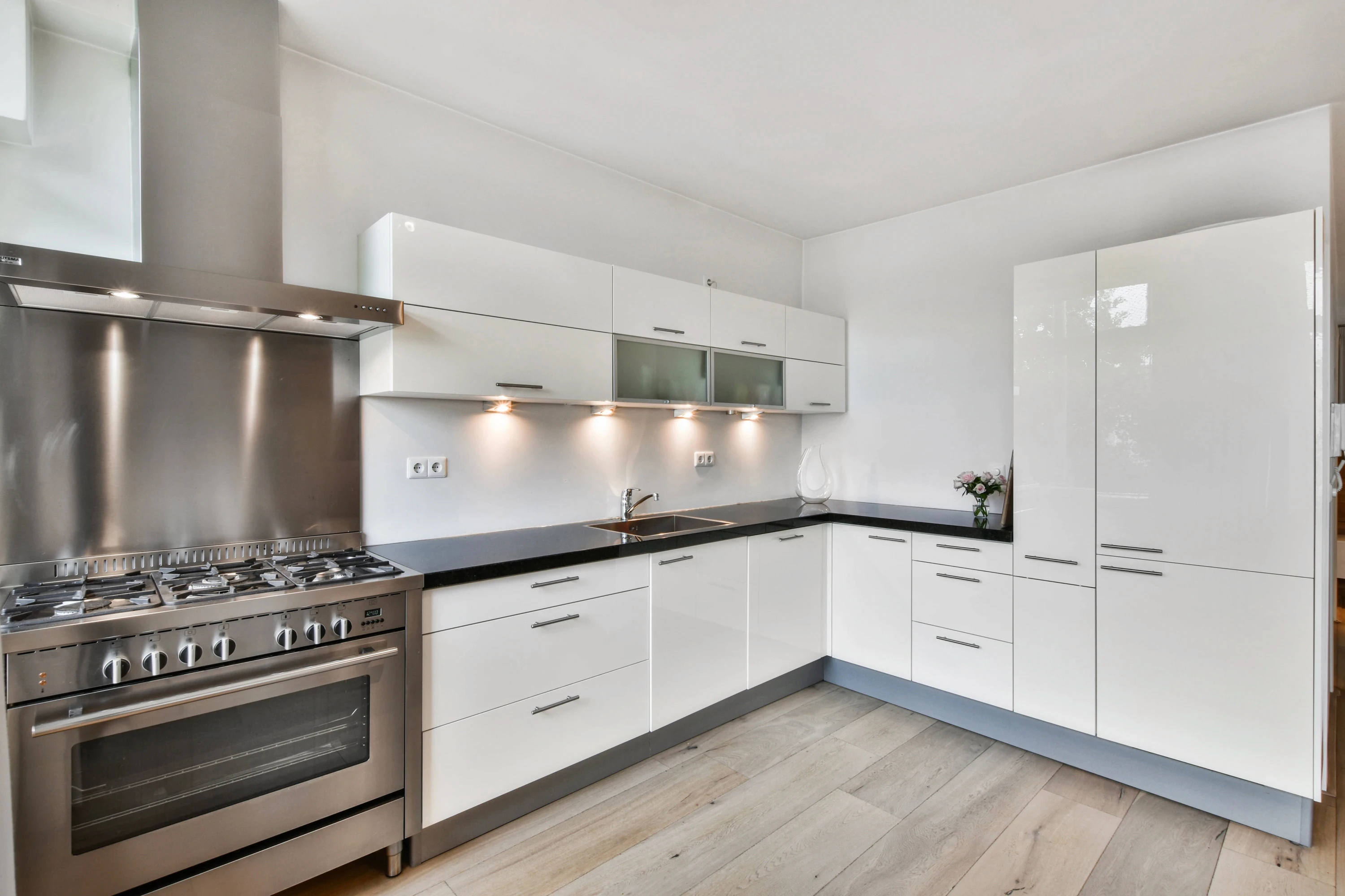 Modern white kitchen with clean lines, stainless steel appliances, and minimalist design.