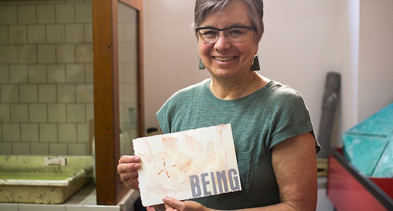a women holding a peper that says being