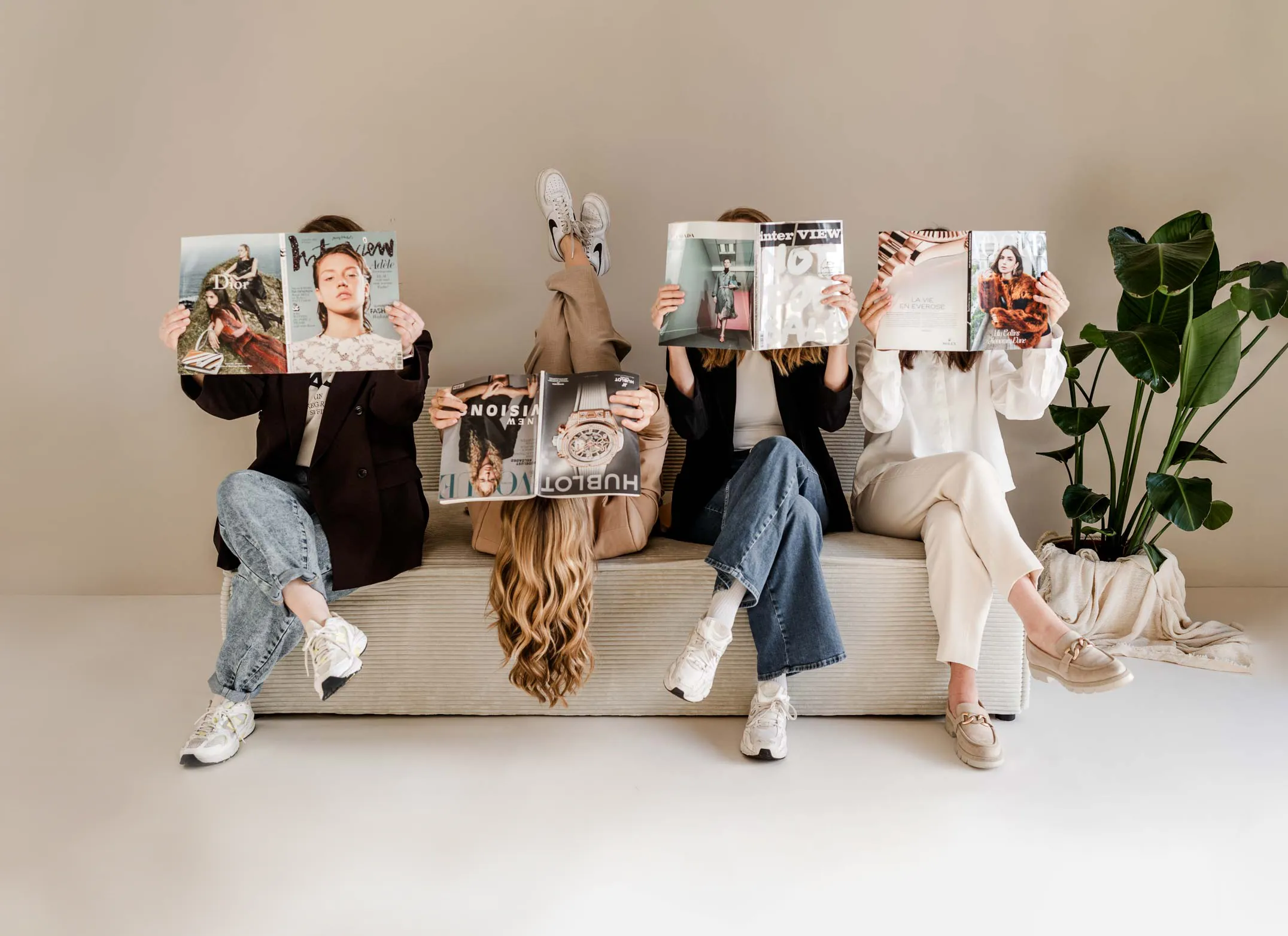 Die vier Mädls von OHNORD studio sitzen auf einer Couch und schauen in ein Magazin über Webdesign und Branding 