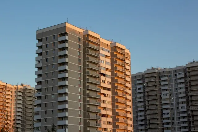 Torres de viviendas con numerosos balcones iluminadas por la luz cálida del atardecer, el conjunto de elementos comunes que protege el seguro de comunidad de propietarios