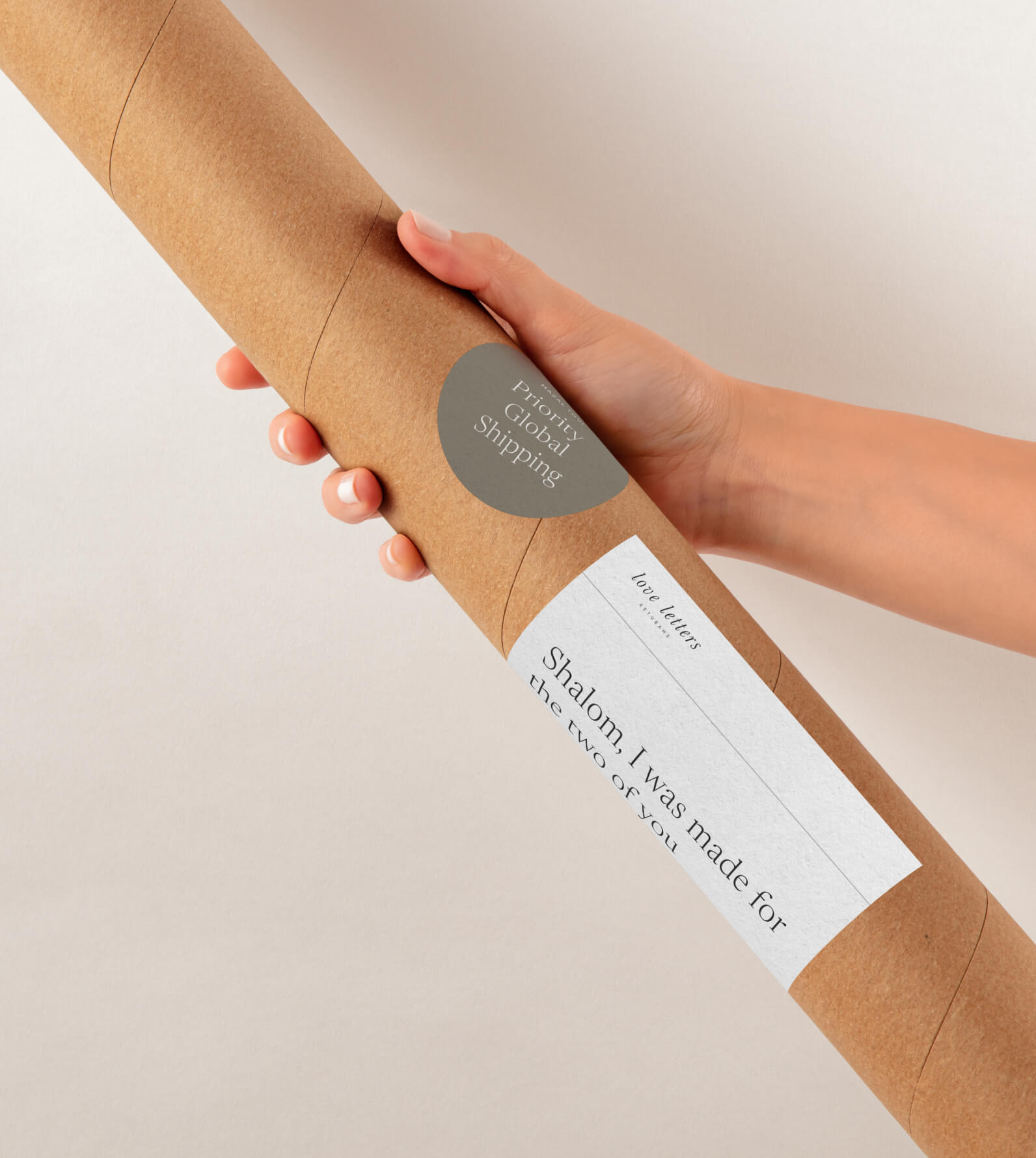 Hand holding a sturdy kraft tube labeled with 'Priority Global Shipping' and 'Shalom, I was made for the two of you,' highlighting free worldwide shipping for all premium ketubah orders.