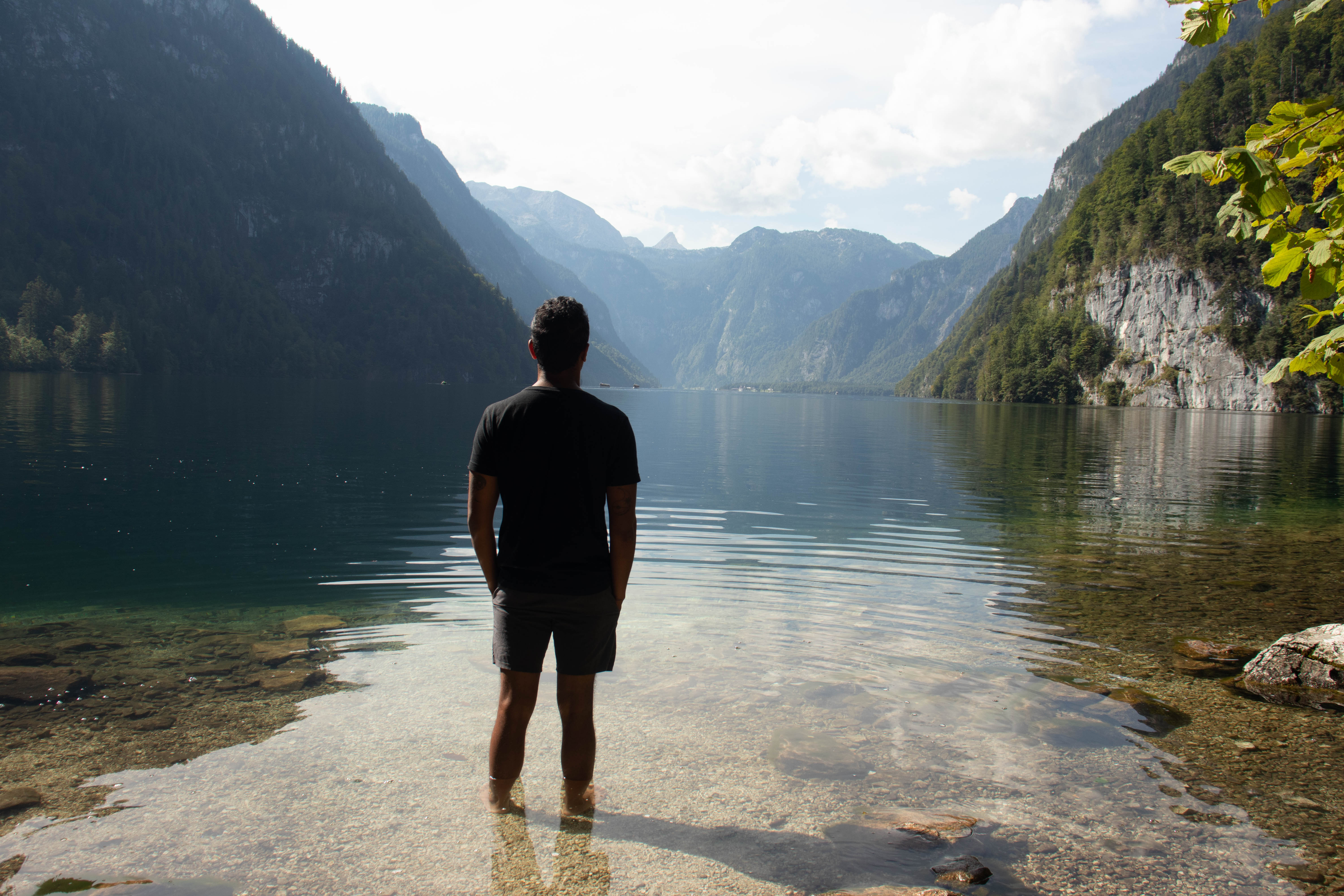 A man standing in clear water looking out at a vast mountain lake, representing the journey toward chronic pelvic pain recovery and physical freedom in Oak Park, IL