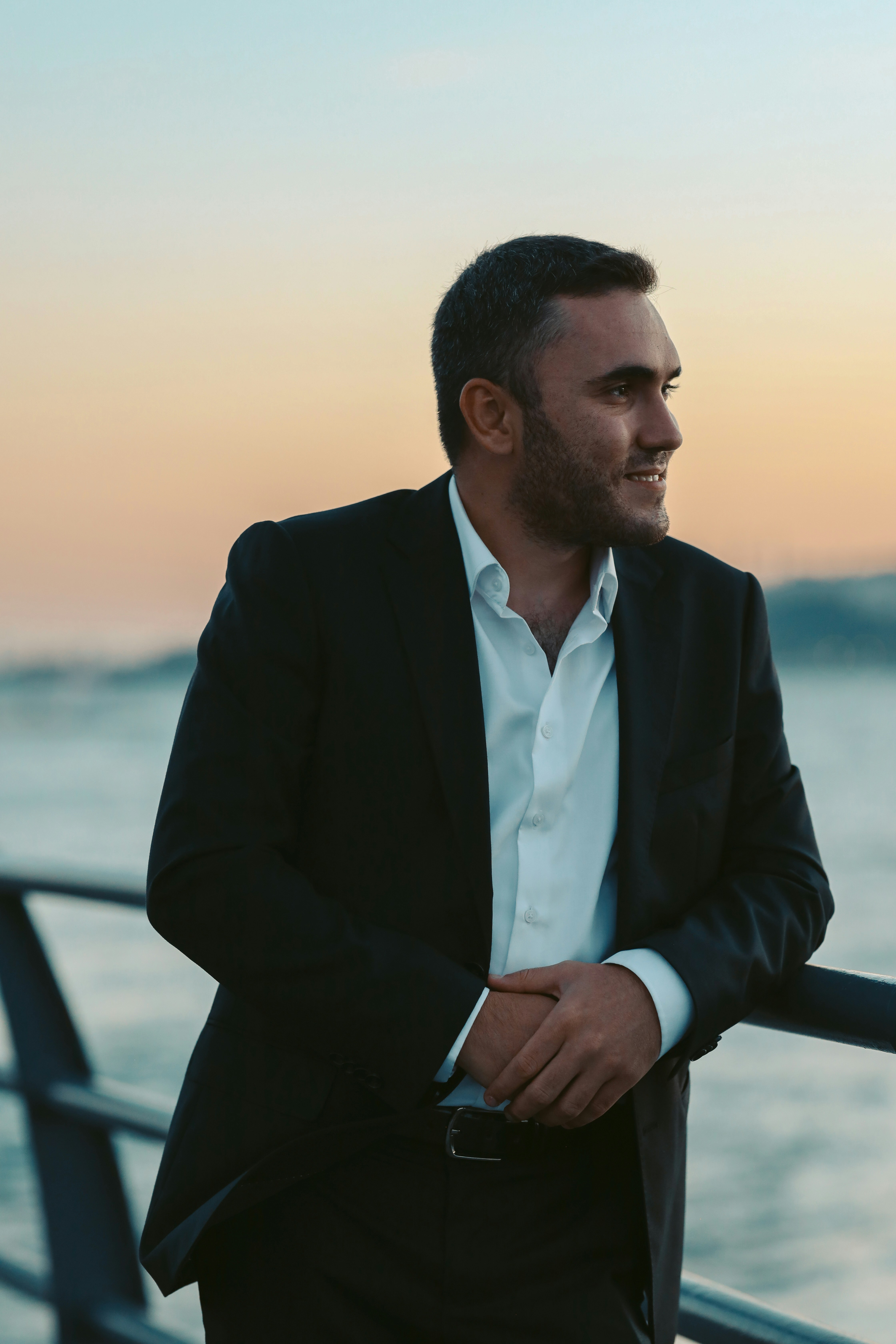 a man in a suit standing next to the ocean