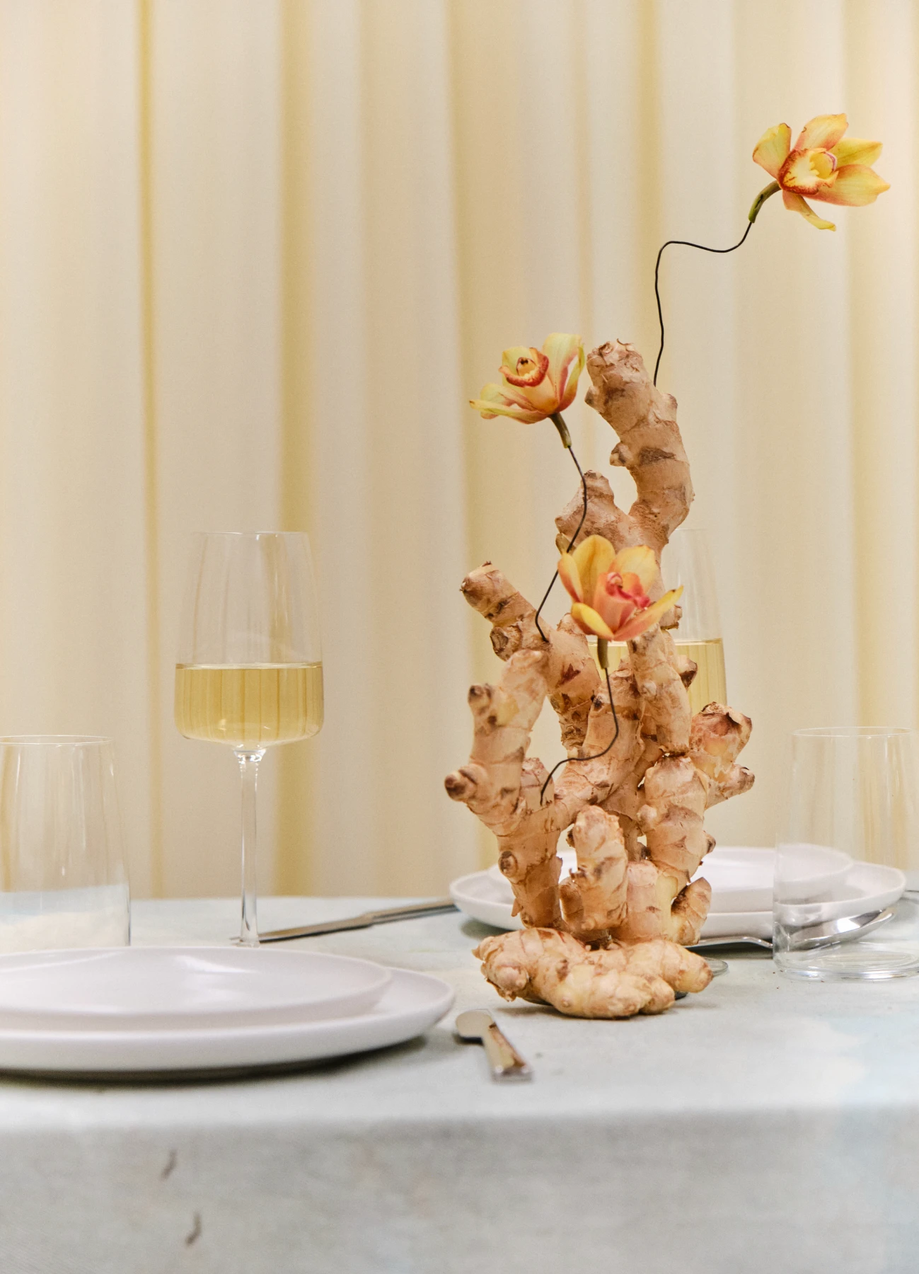 Instalación floral contemporánea con flores rojas y fucsias sobre mesas blancas.