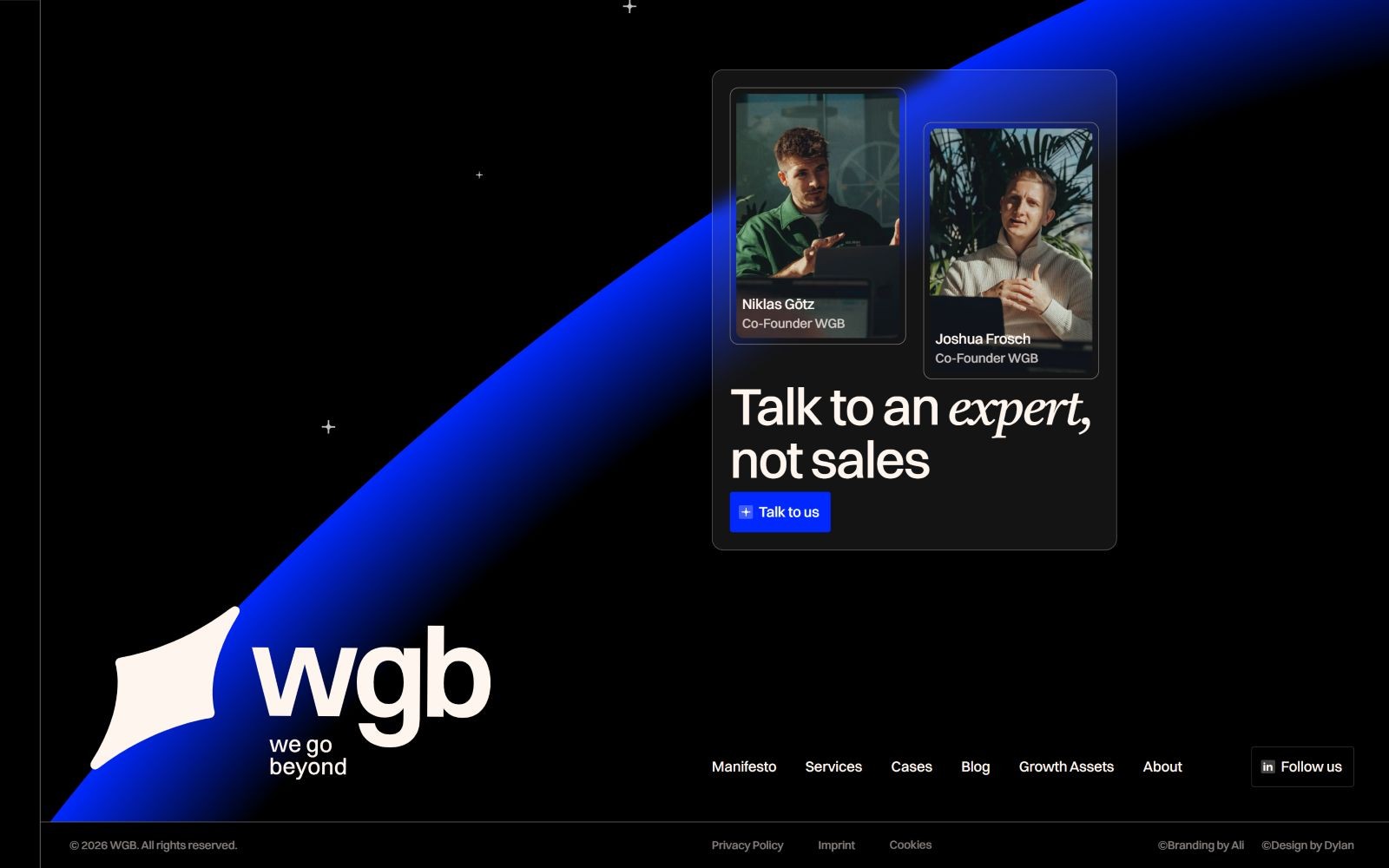 A dark-themed website with a blue swoosh. Two portraits labeled "Niklas Götz" and "Joshua Freundt." Text: "Talk to an expert, not sales.