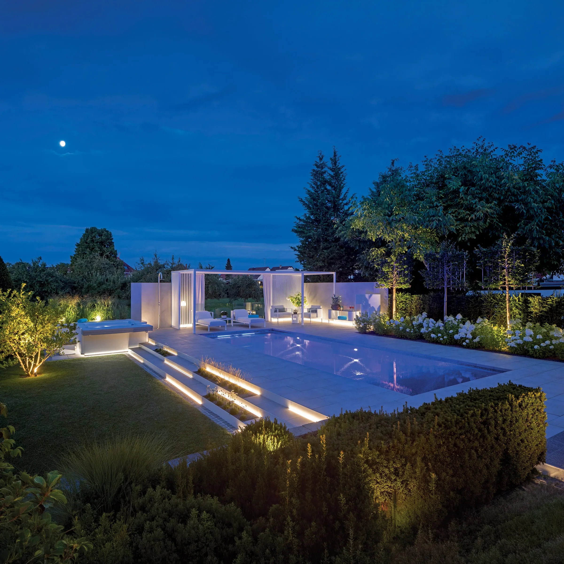MLine Schwimmbad bei Nacht mit beleuchteten Stufen, weißer Pergola und Gartenanlage