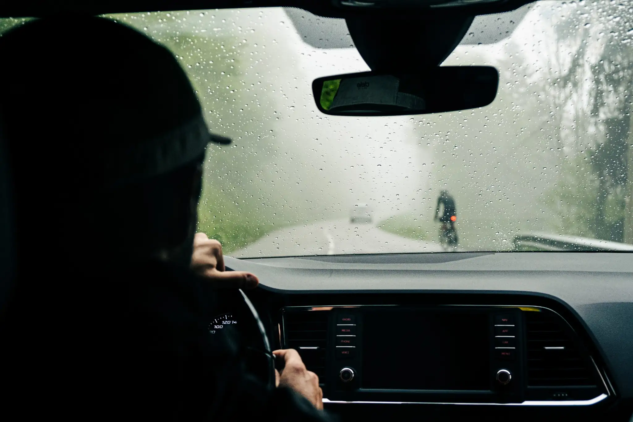 Voiture suivant cycliste dans la pluie