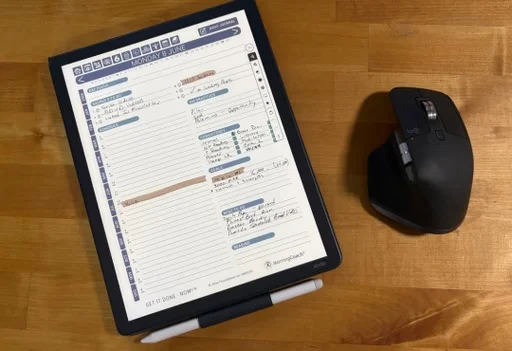 E-ink planner with handwritten notes beside a computer mouse on a desk
