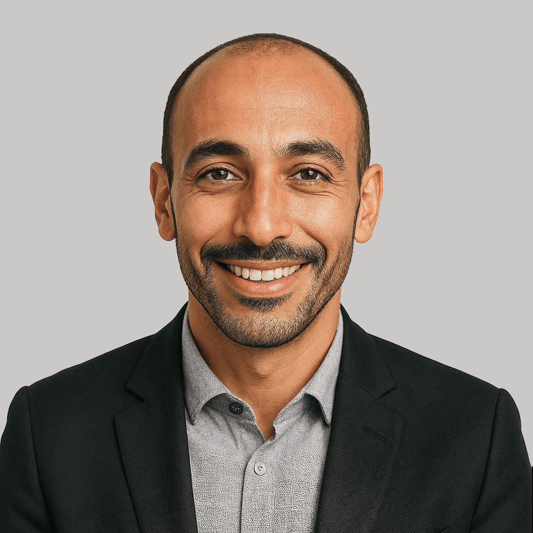 Smiling man in a black suit and gray shirt, professional headshot