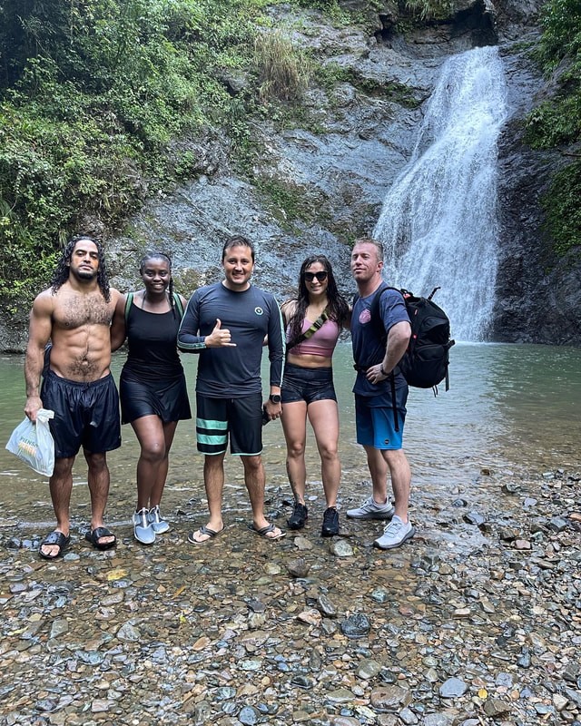Film crew and subjects posing together at a waterfall in Puerto Rico