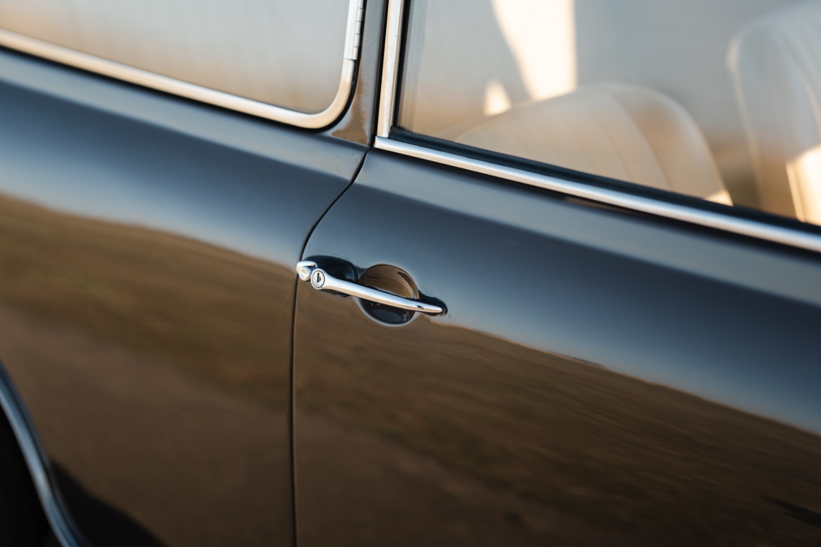 Close-up of a car door handle on a vehicle with a gleaming surface and soft lighting.