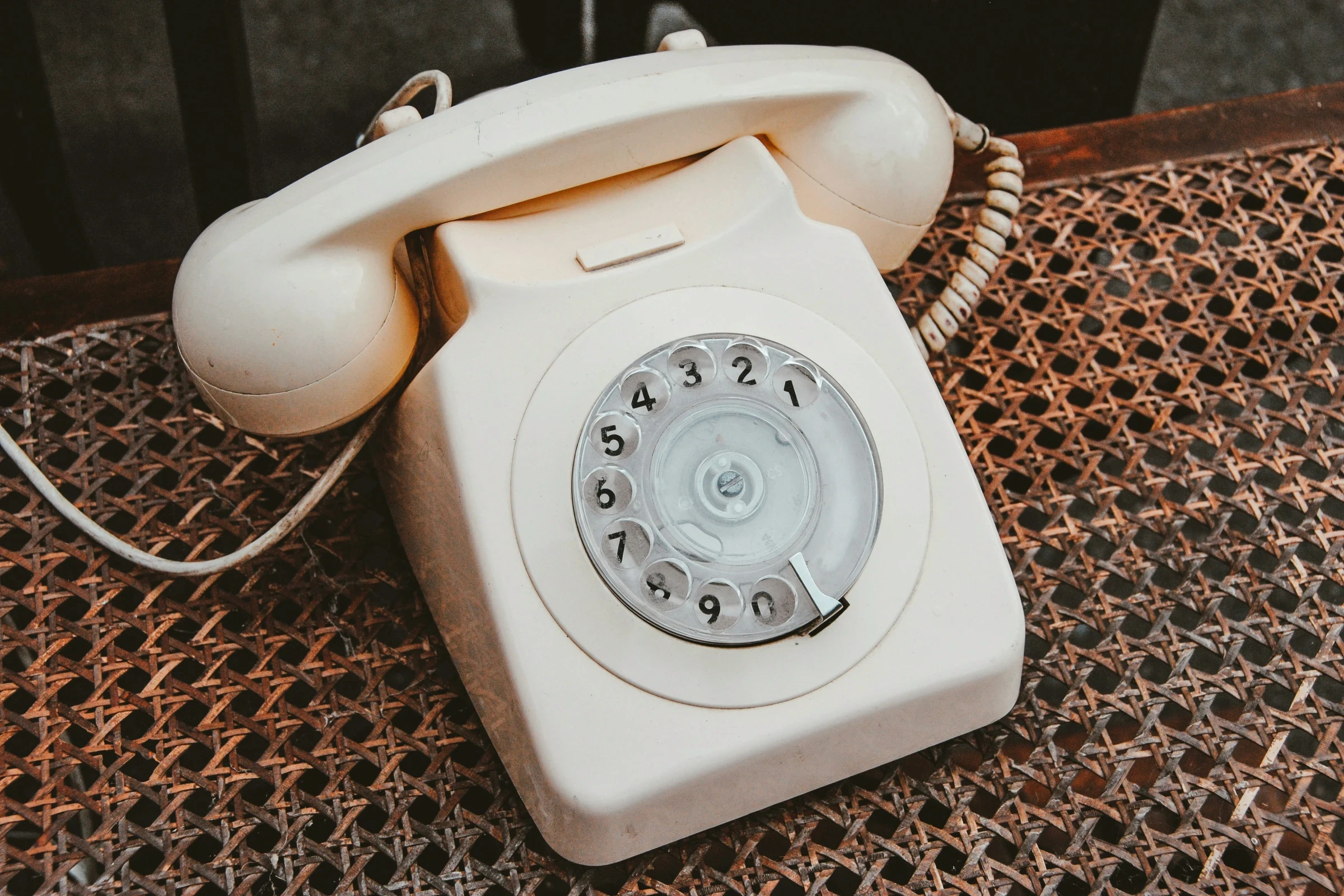 Kremowy telefon z tarczą na plecionym siedzisku