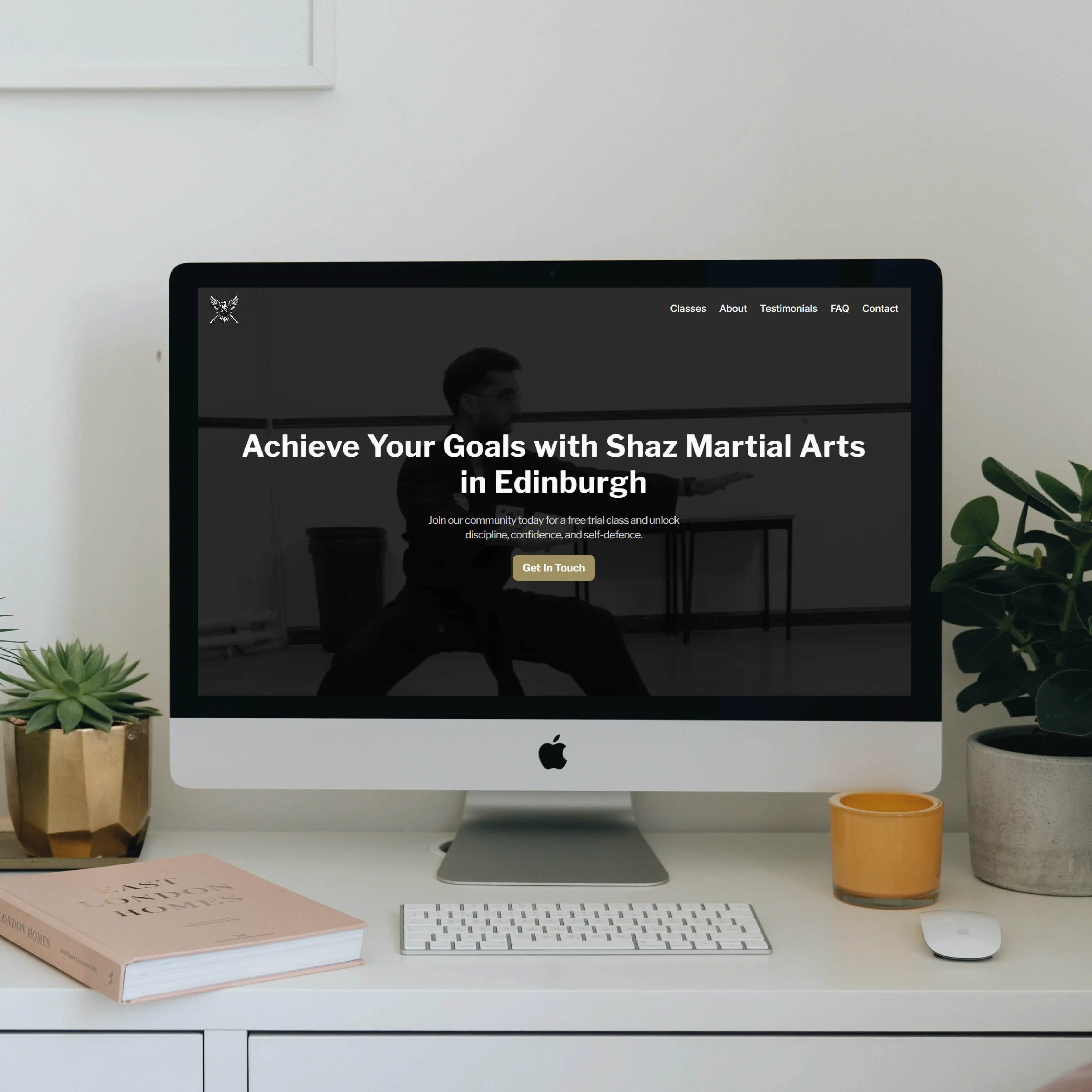 iMac displaying the homepage of Shaz Martial Arts, sitting on a white desk