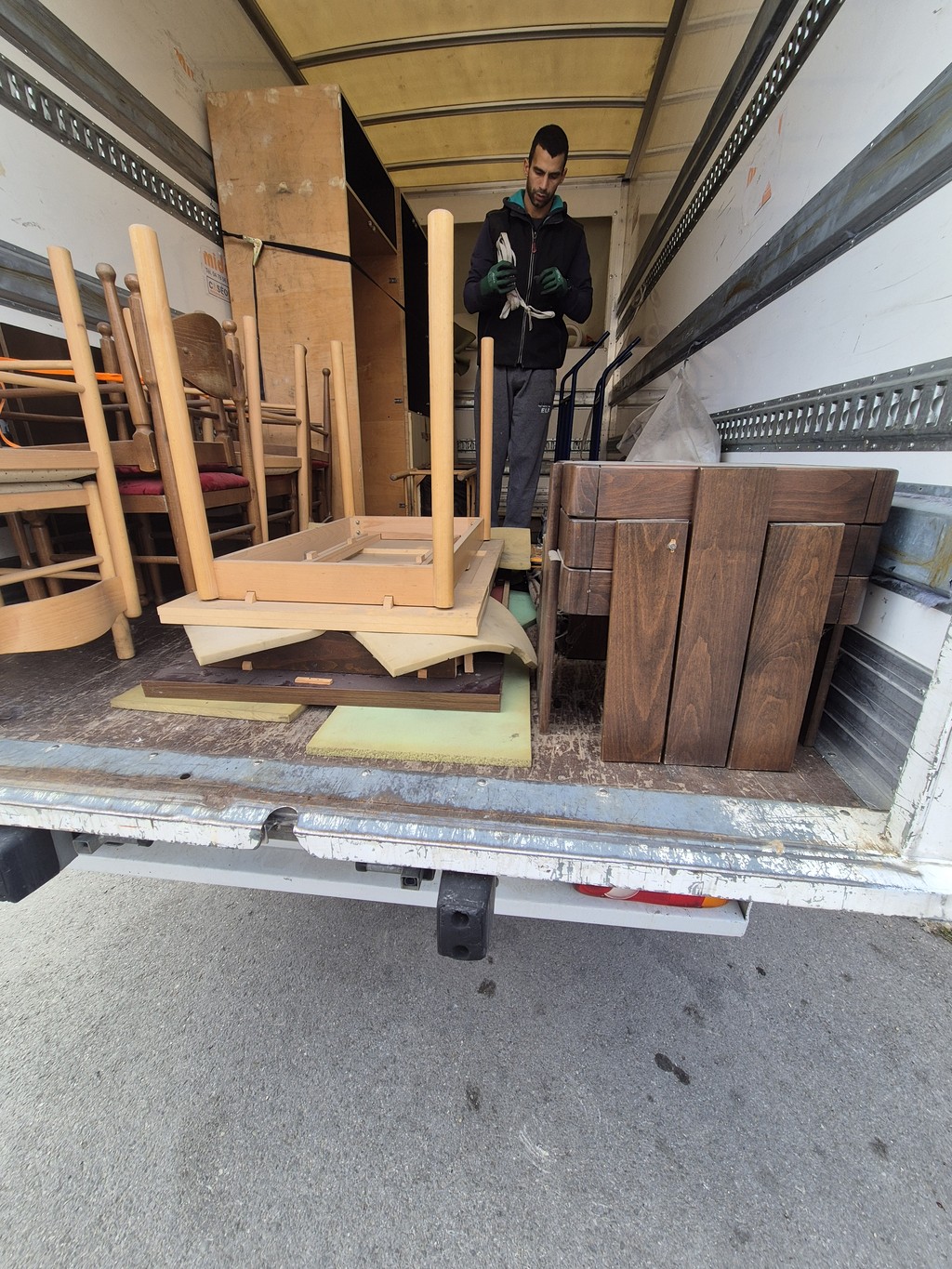 Radnik pažljivo pakuje i organizuje nameštaj u kamionu za selidbe, uz uredno složene stolice i ormare, što prikazuje profesionalnu i bezbednu uslugu preseljenja u Beogradu.