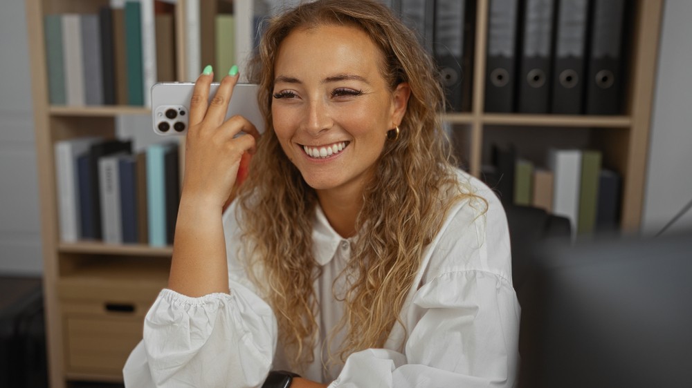 Femme souriante tenant un téléphone, illustrant l'exploration des différences entre assurance hypothécaire et assurance-vie.