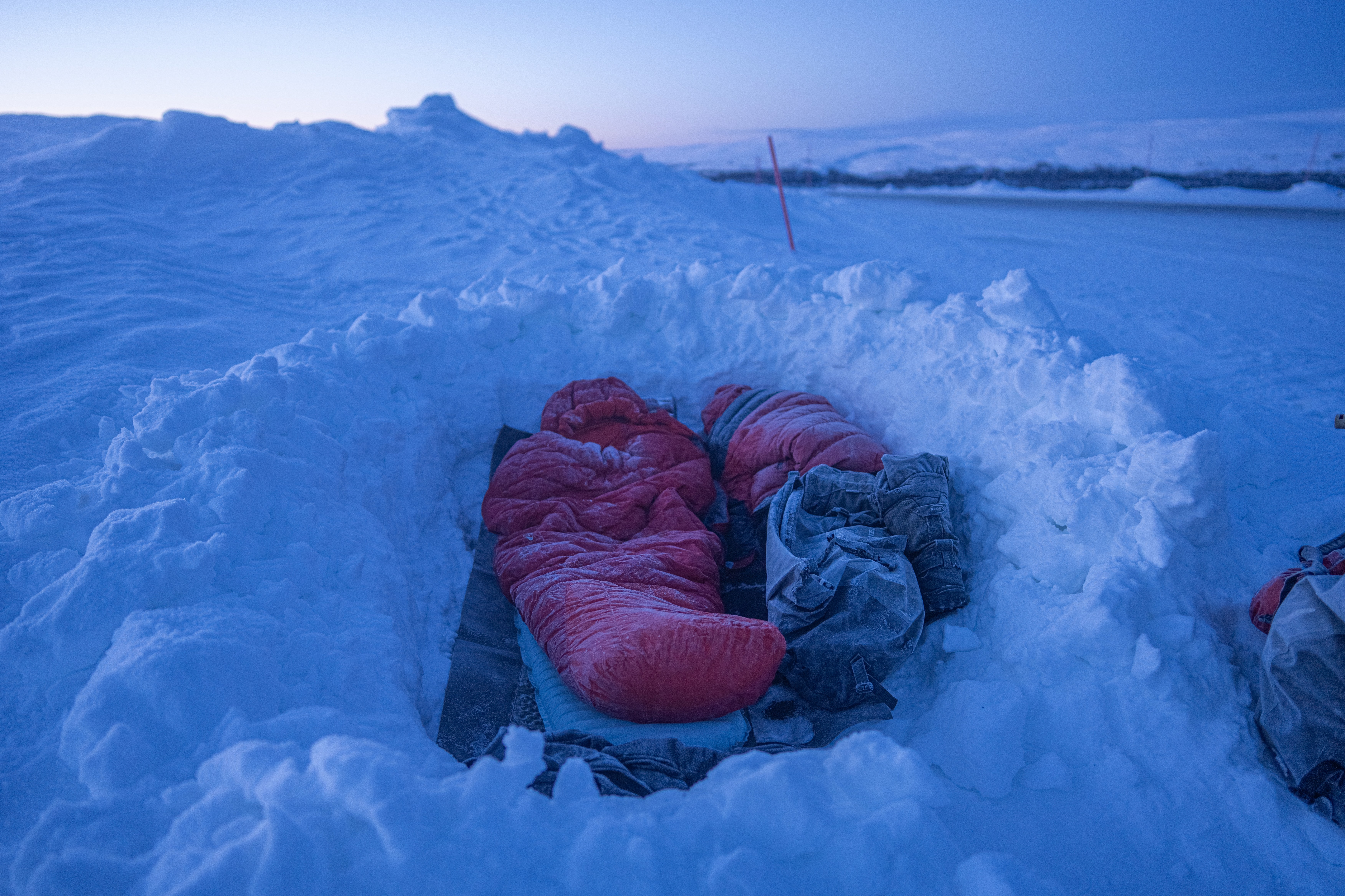 Sleeping bags in a snow shelter at dusk