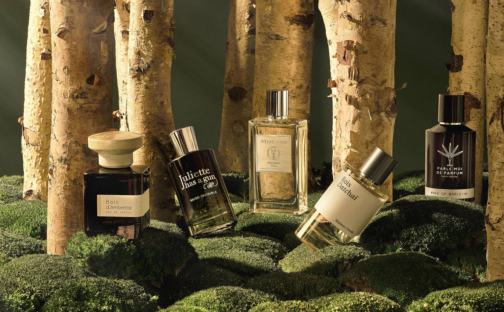 Luxury perfume bottles displayed in a forest setting on moss.