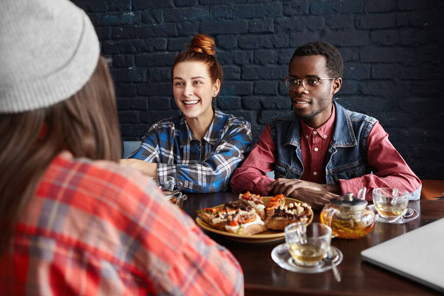 A fashionable African male in stylish attire, smiling and posing with friend, enjoying the vibrant atmosphere at Yajee - African & Caribbean Cuisine.