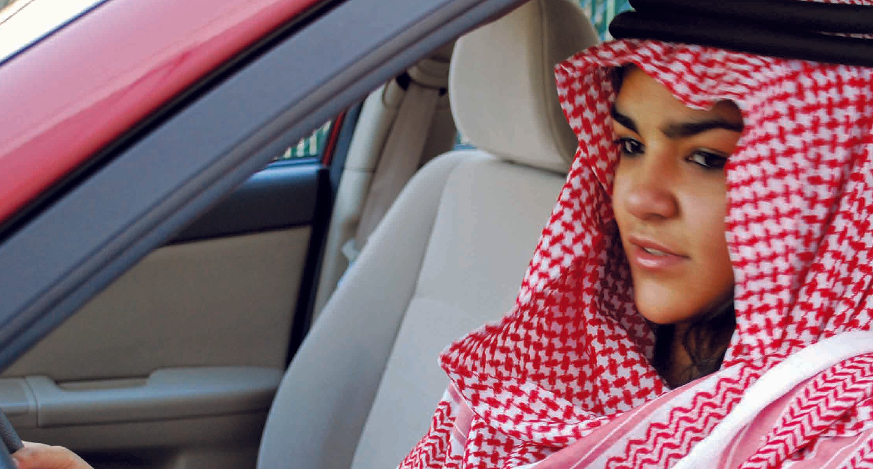 A photo of an Arab woman driving a red car.
