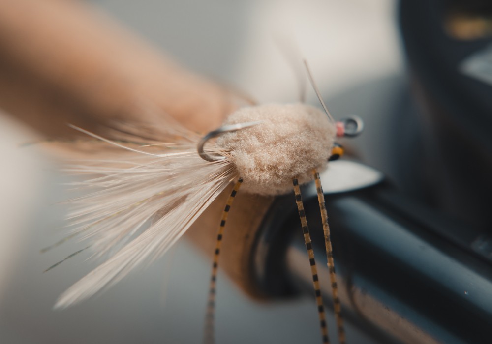 Closeup of a raghead fly on top of a fly fishing rod handle