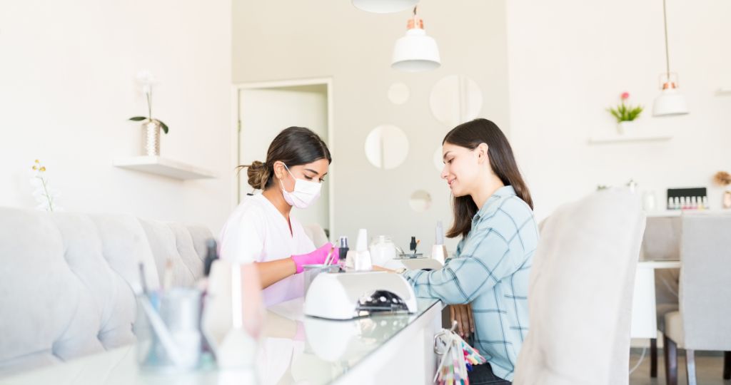 Nail technician providing a manicure to a client in a salon.