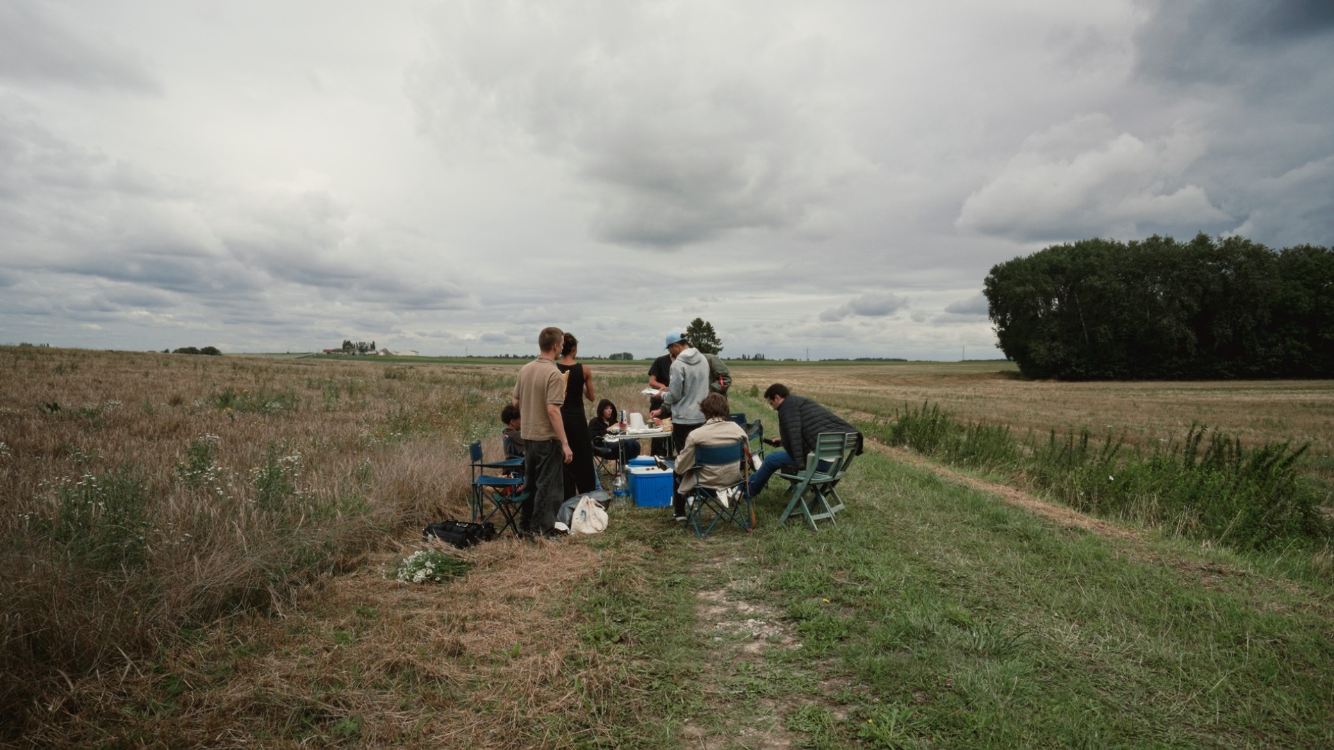 Équipe de tournage rassemblée autour d'une table en pleine nature pour une pause déjeuner.