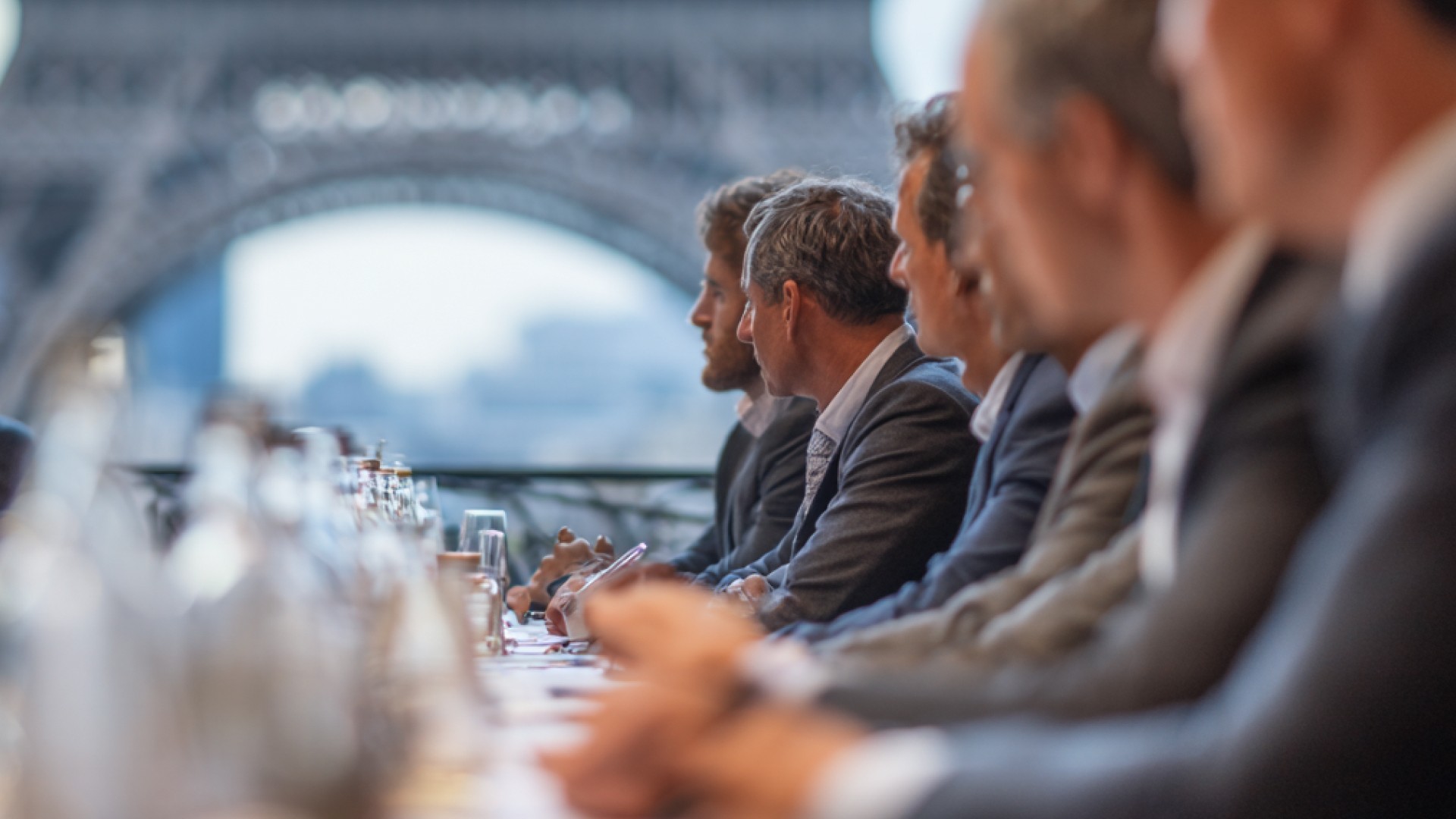 Delegates and financial crime experts seated around a conference table in Paris with the Eiffel Tower in the background, representing discussions and outcomes from the FATF Plenary on AML and sanctions compliance.