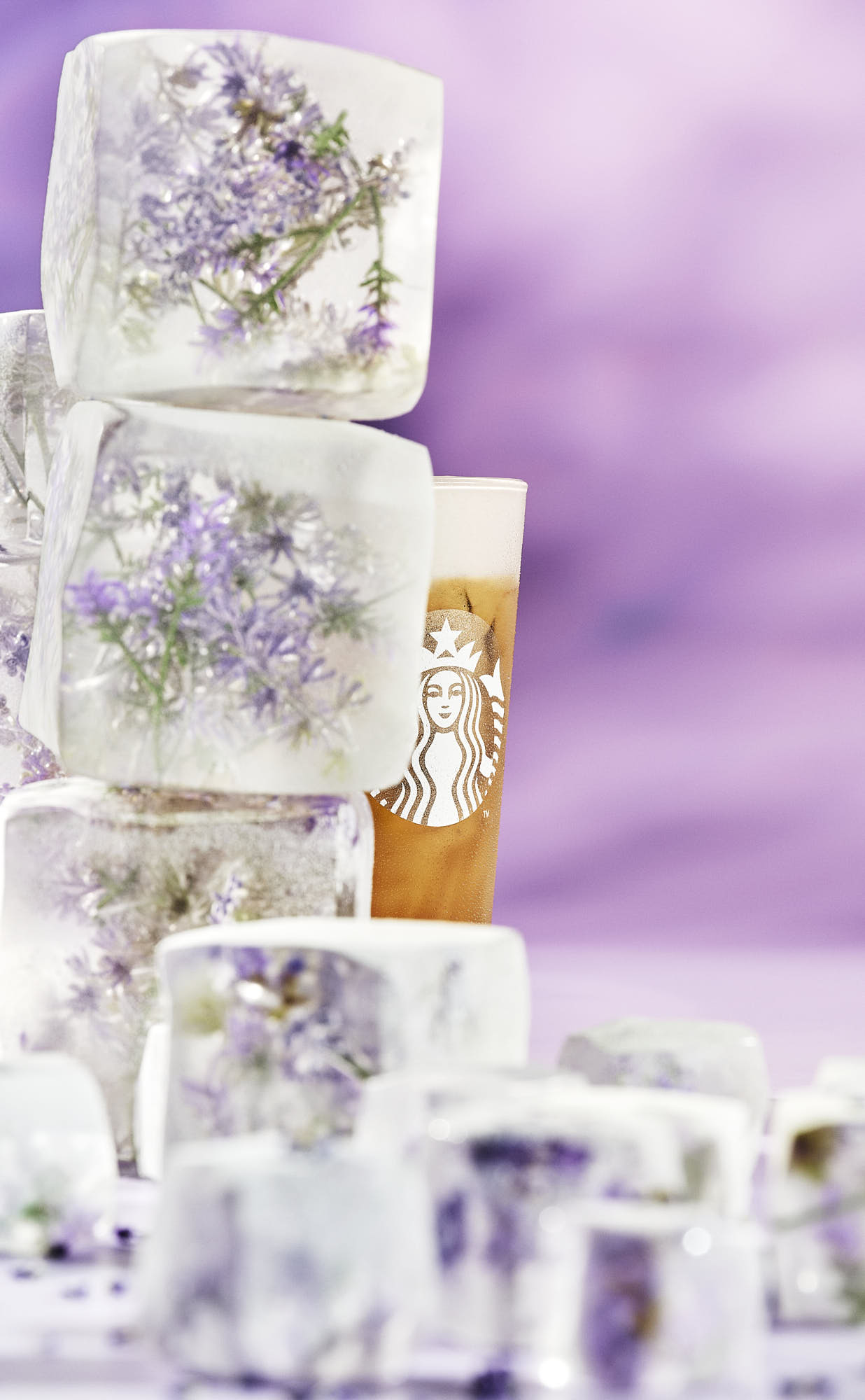 Stack of artistic ice featuring intricate floral designs, set against a soft purple background.