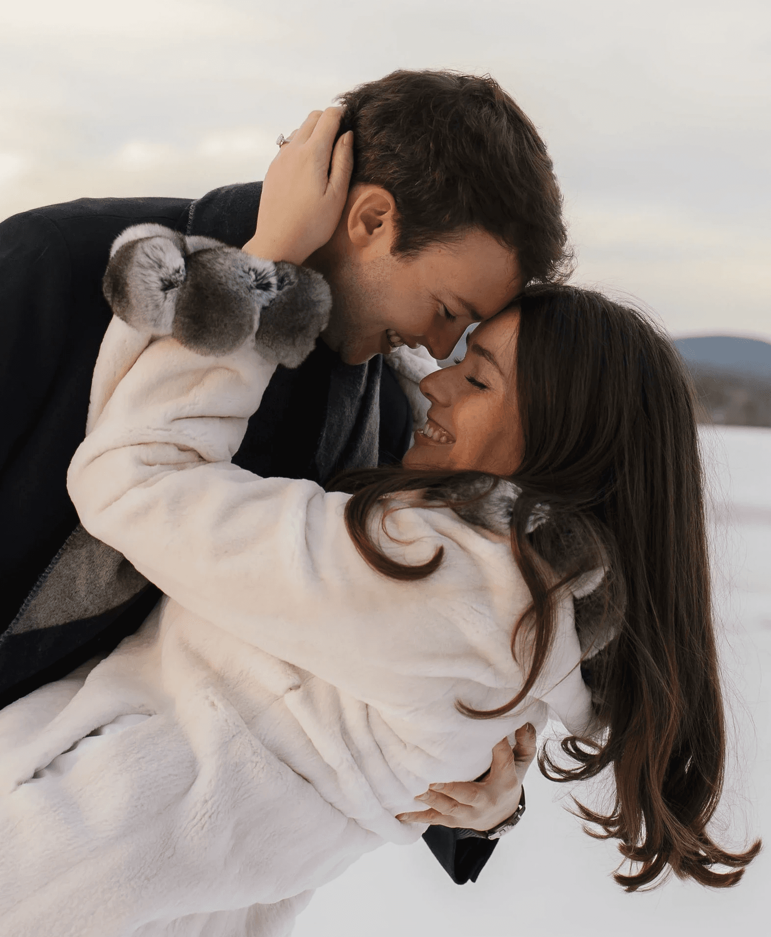 A couple embraces lovingly on a wooden dock.