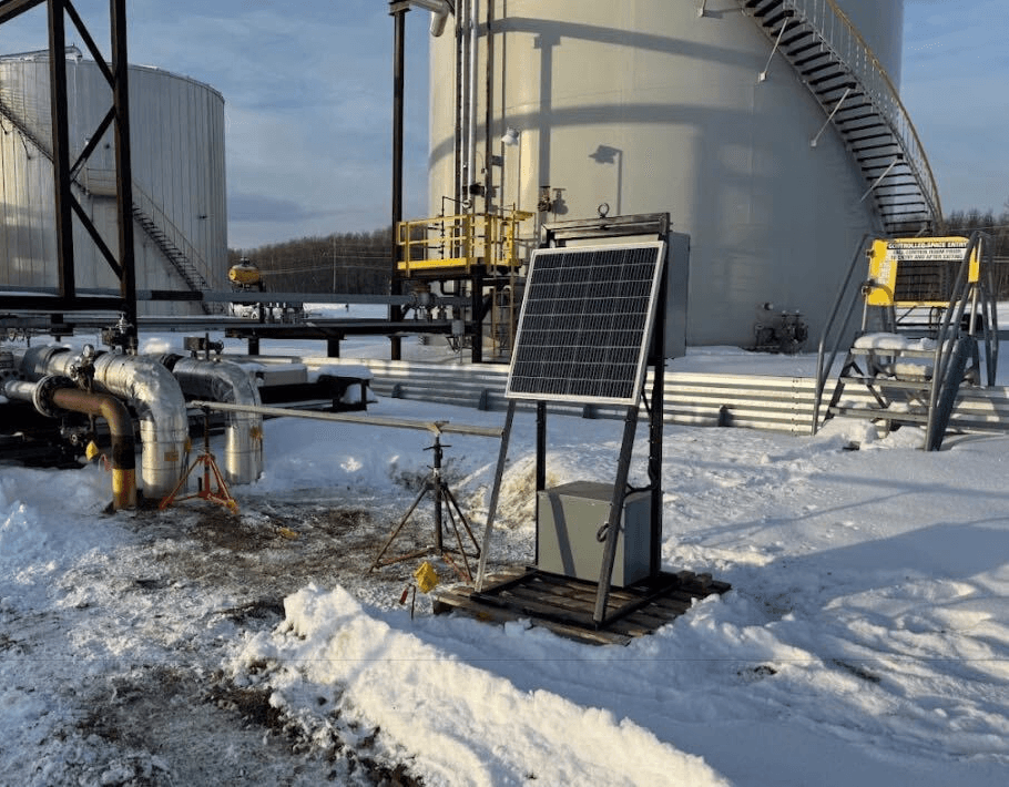 Close-up portrait of a person wearing a gray insulated hooded jacket with the hood up, showing their face framed by the hood against a light background.