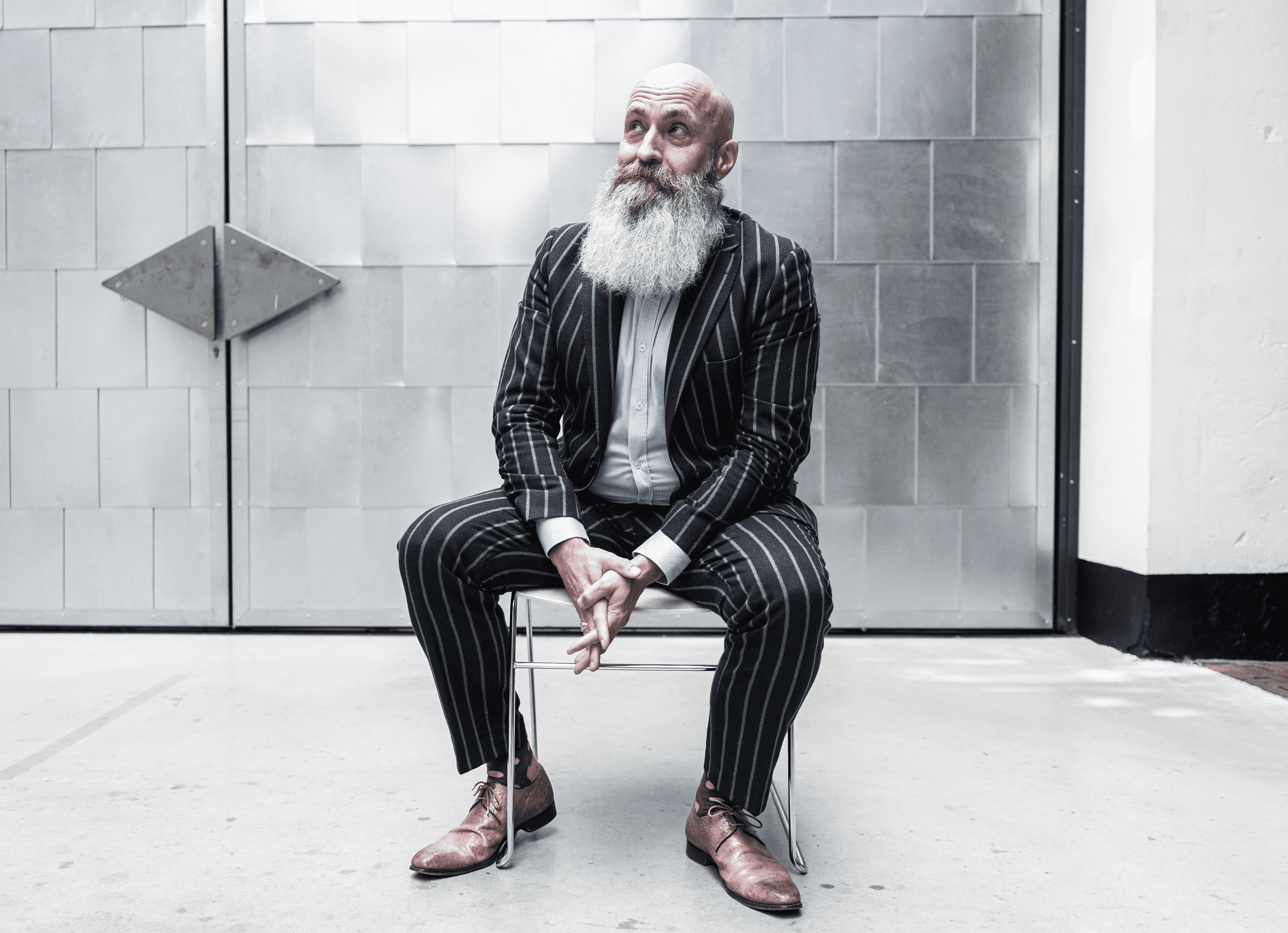 Bas Stronks, oprichter van wdb?, grinnnekend op stoel in industriele setting.