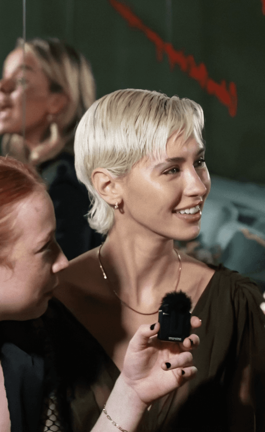 Dancer in black outfit with arms raised, arching backwards