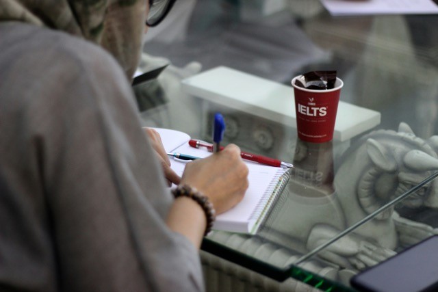A student taking notes to prepare for IELTS exam