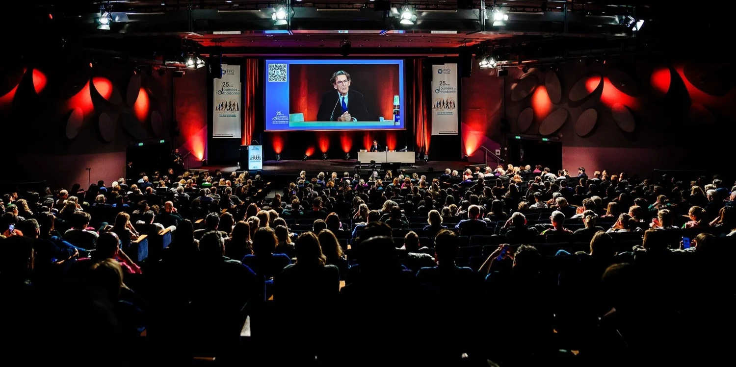 Close-up of two smiling friends with freckles, bright makeup, on a light blue background—joyful, inclusive brand portrait.