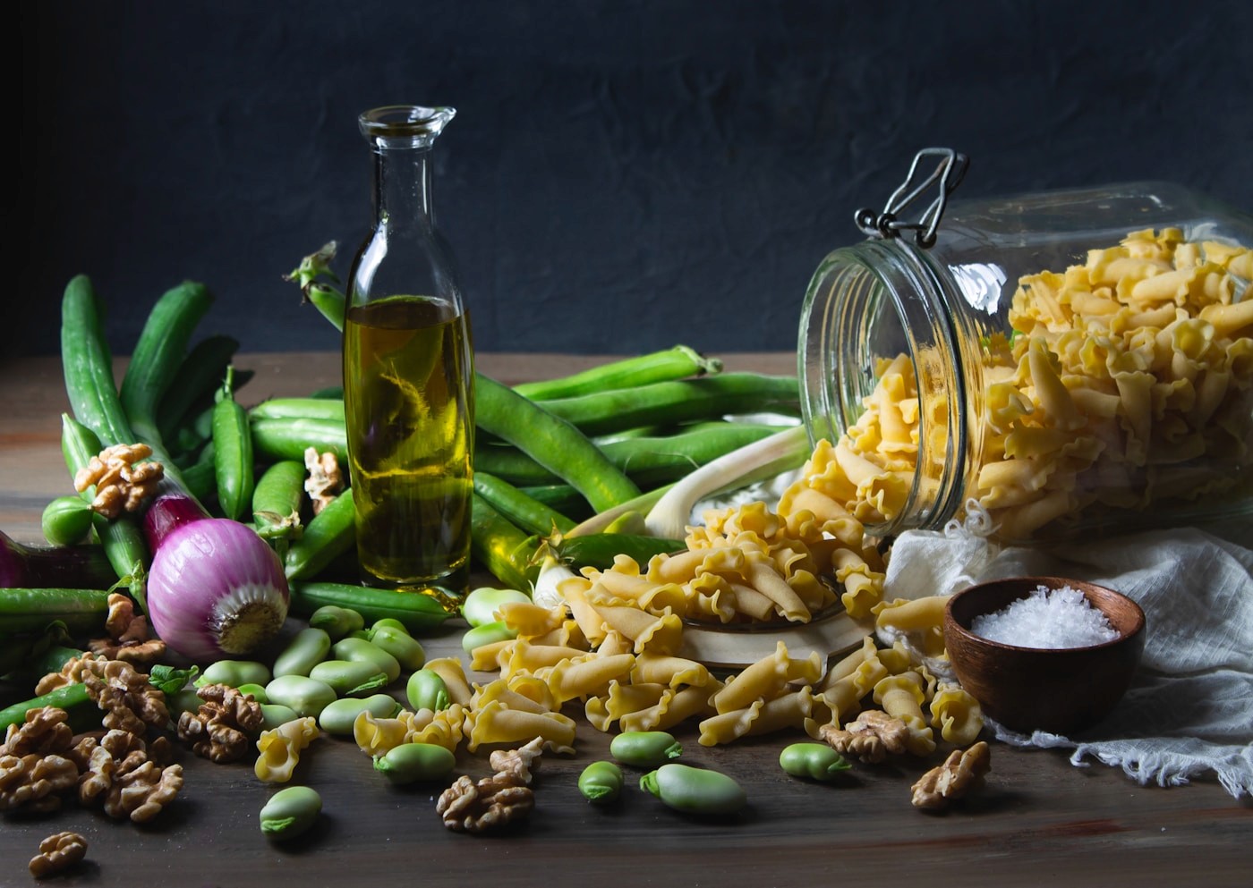 Olive oil, green beans, legumes, nuts, and whole-grain pasta laid out together, representing a Mediterranean-style eating pattern.
