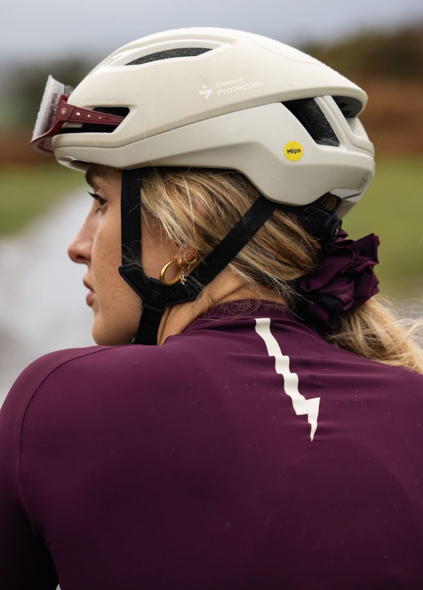 Side-close-up-of-a-cyclist-wearing-a-burgundy-long-sleeve-cycling- jersey-with-a-white-lightning-bolt- graphic-on-the-back
