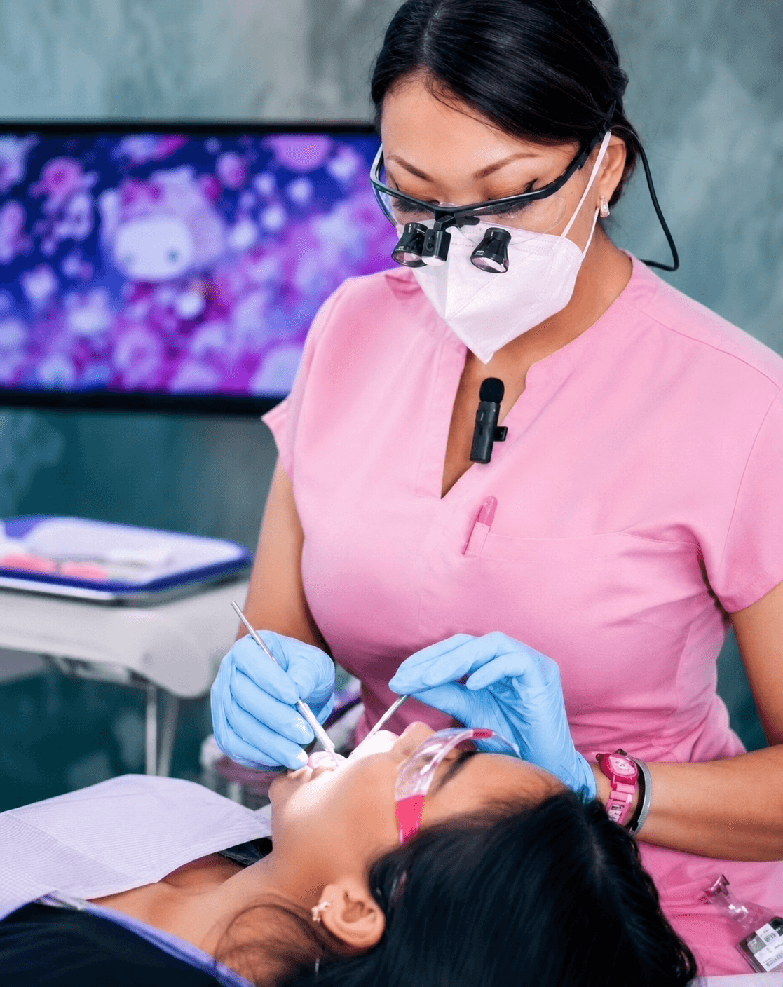 Vivienne Frederiksen providing preventive dental care to a patient while wearing magnification loupes and protective equipment.