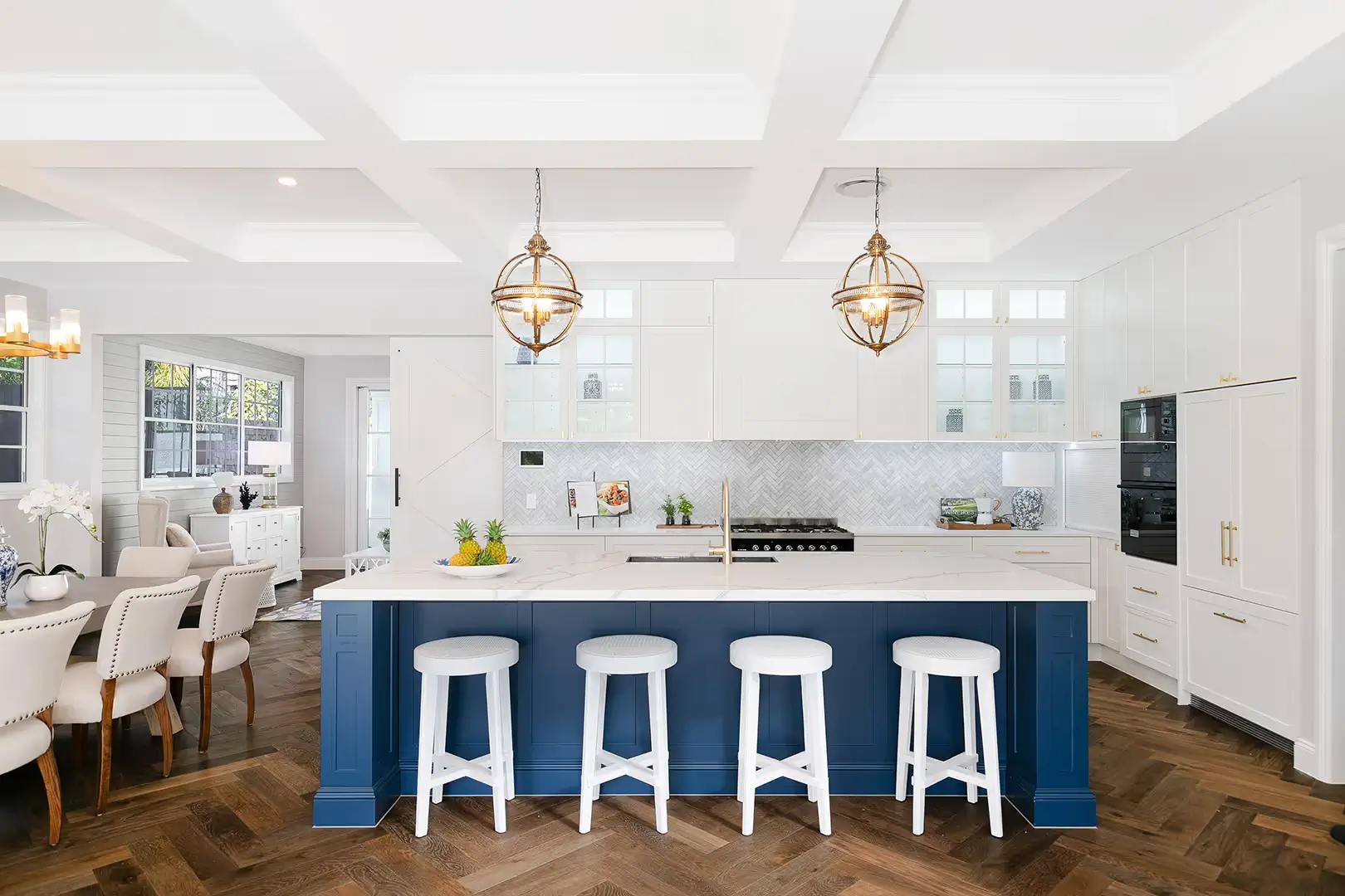 A kitchen with coffered ceilings and two lights over the island bench