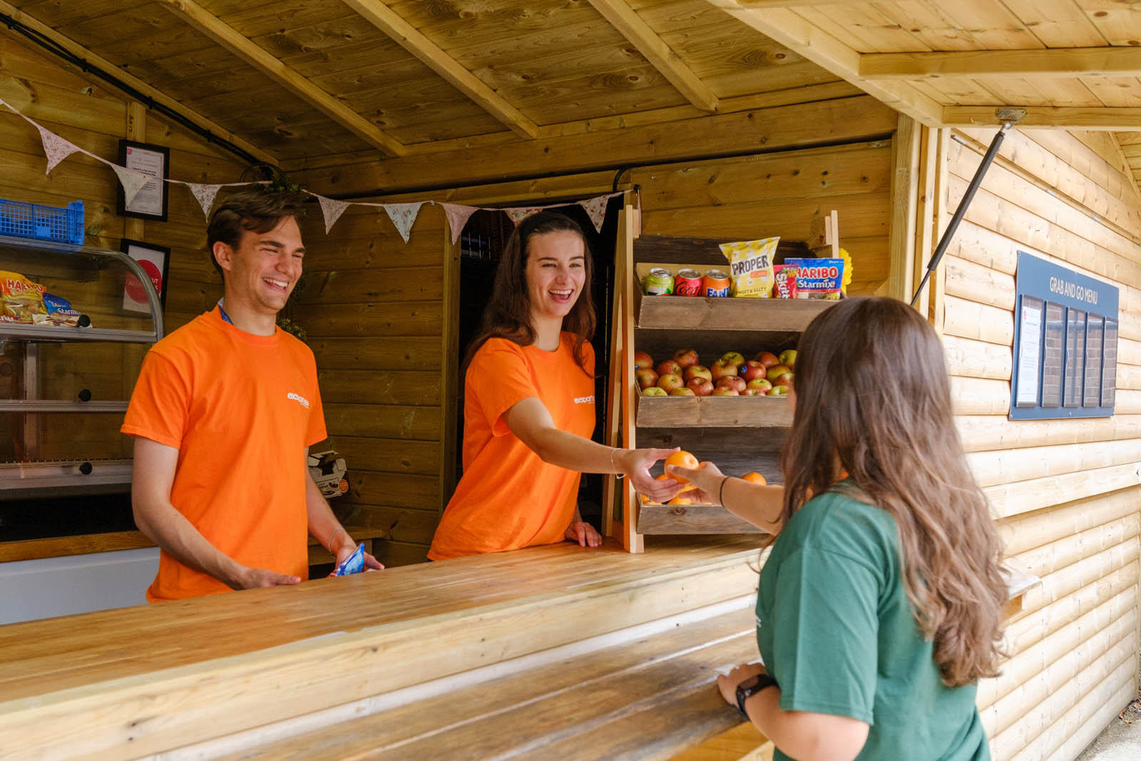 staff members giving a student a piece of fruit from the tuck shop.
