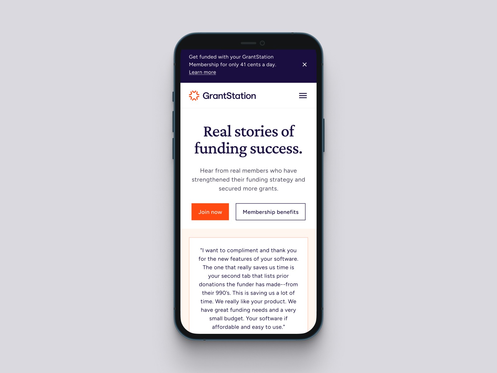 Mobile phone displaying the GrantStation website with the headline “Real stories of funding success.”
