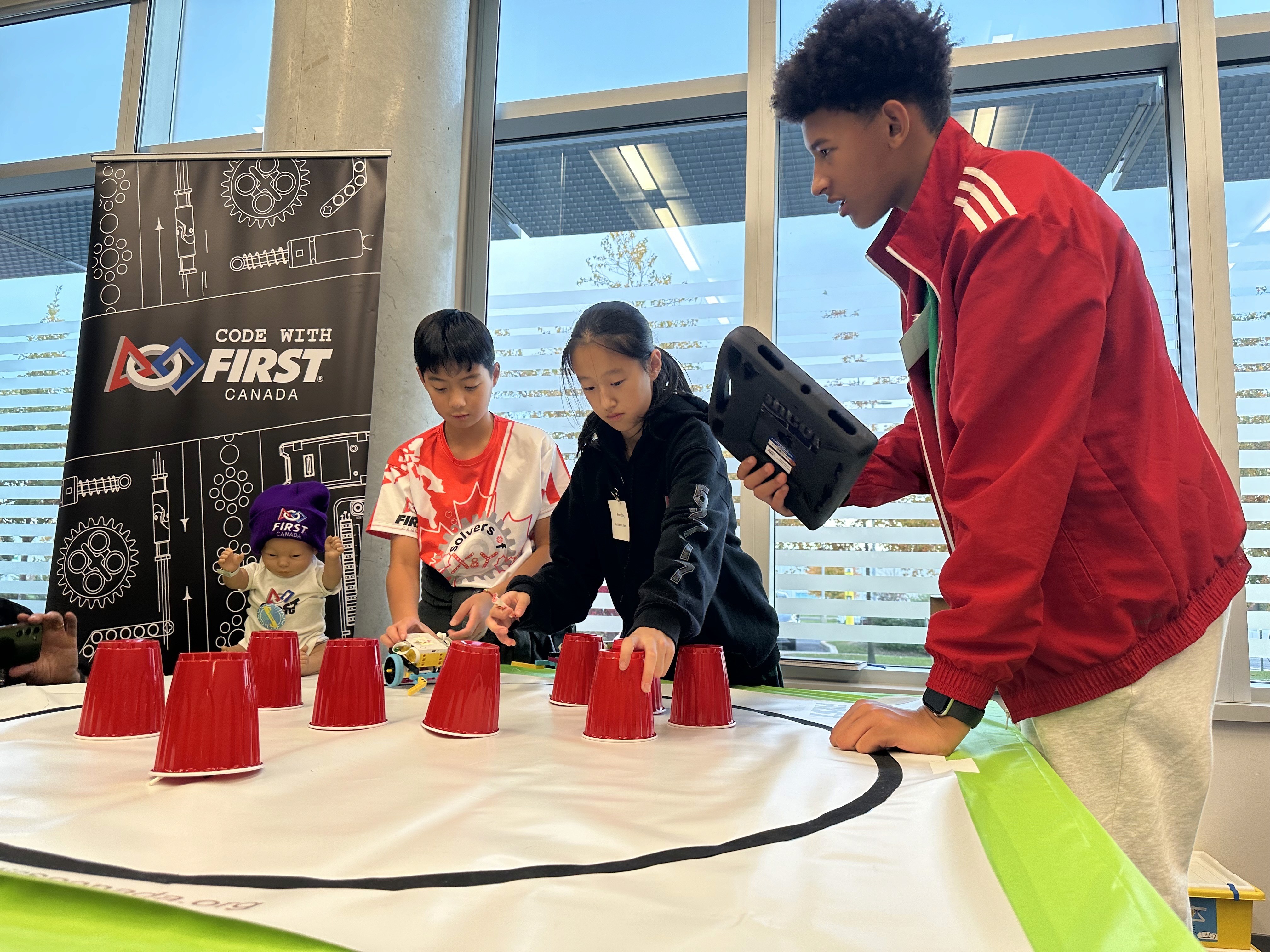 SolversMind FLL students, Renee Zhang, Samuel Pan and Amani showcase FIRST robotics programs to Honda employees and families during the 2025 Halloween celebration.
