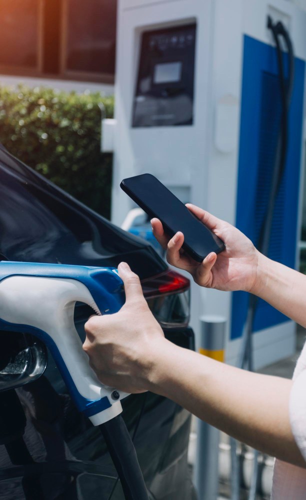 A person holding the phone in the petrol station.