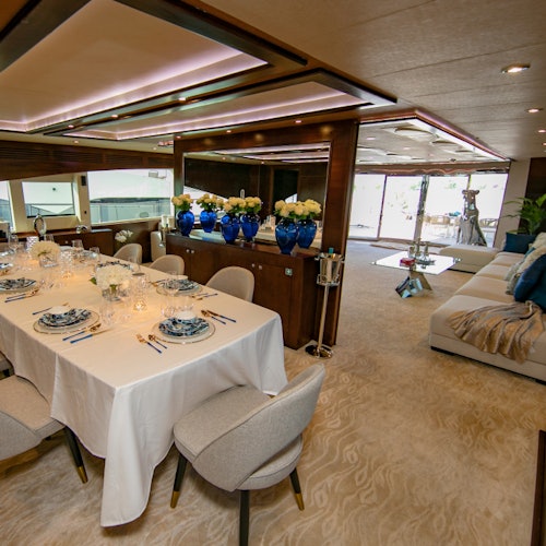 一間豪華的餐廳，桌上為六個人擺設，裝飾著藍白色的碟子，背景有一個舒適的休息區。