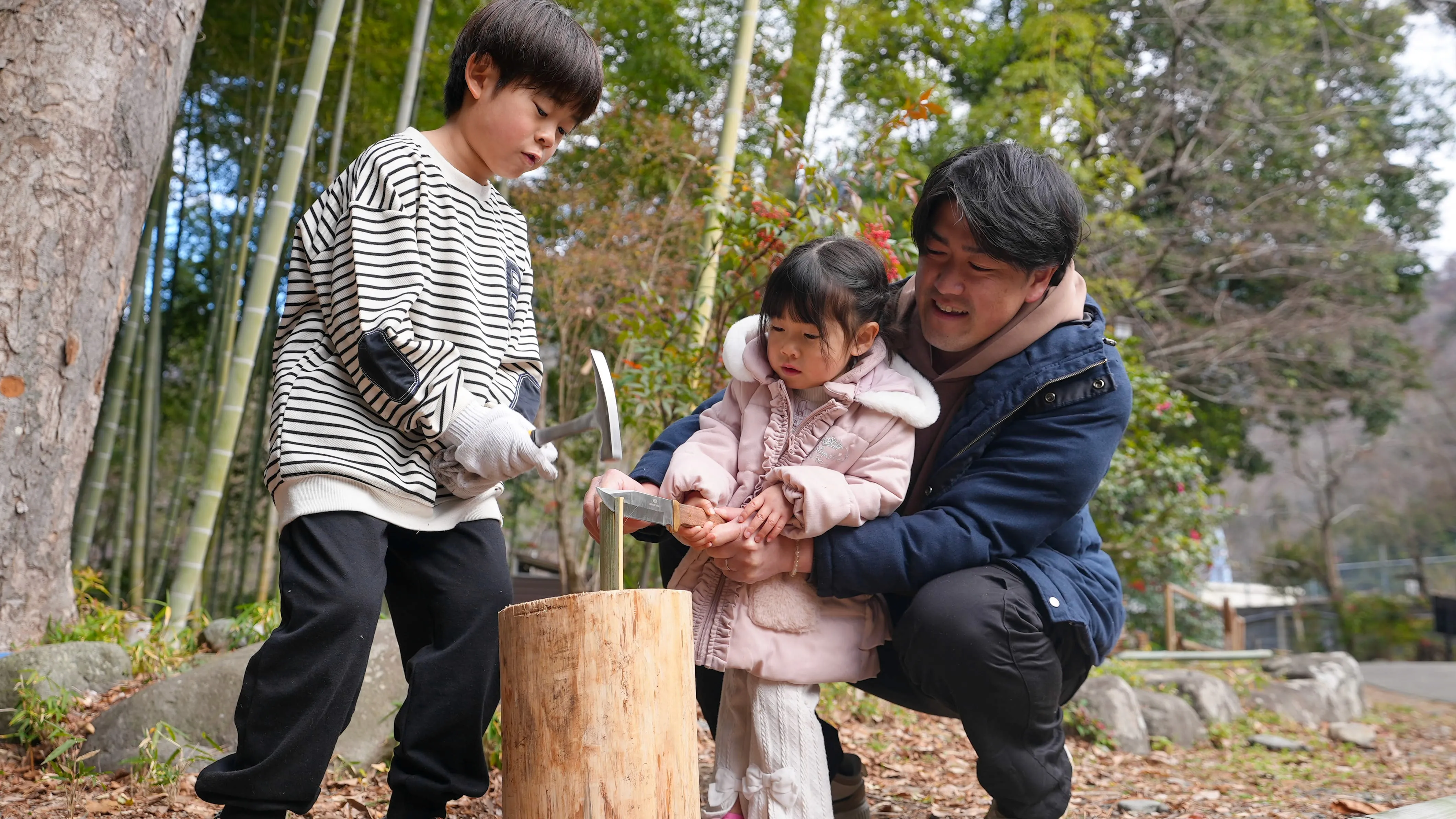 An energetic indoor performance by Japanese taiko drummers, their arms a blur of motion as they powerfully strike a massive ōdaiko drum with wooden sticks in front of an audience. In the background, a row of lit paper lanterns hangs from the ceiling.