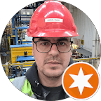 Close-up portrait of a freckled woman with soft pink hair and star earring, natural light, white tank top.