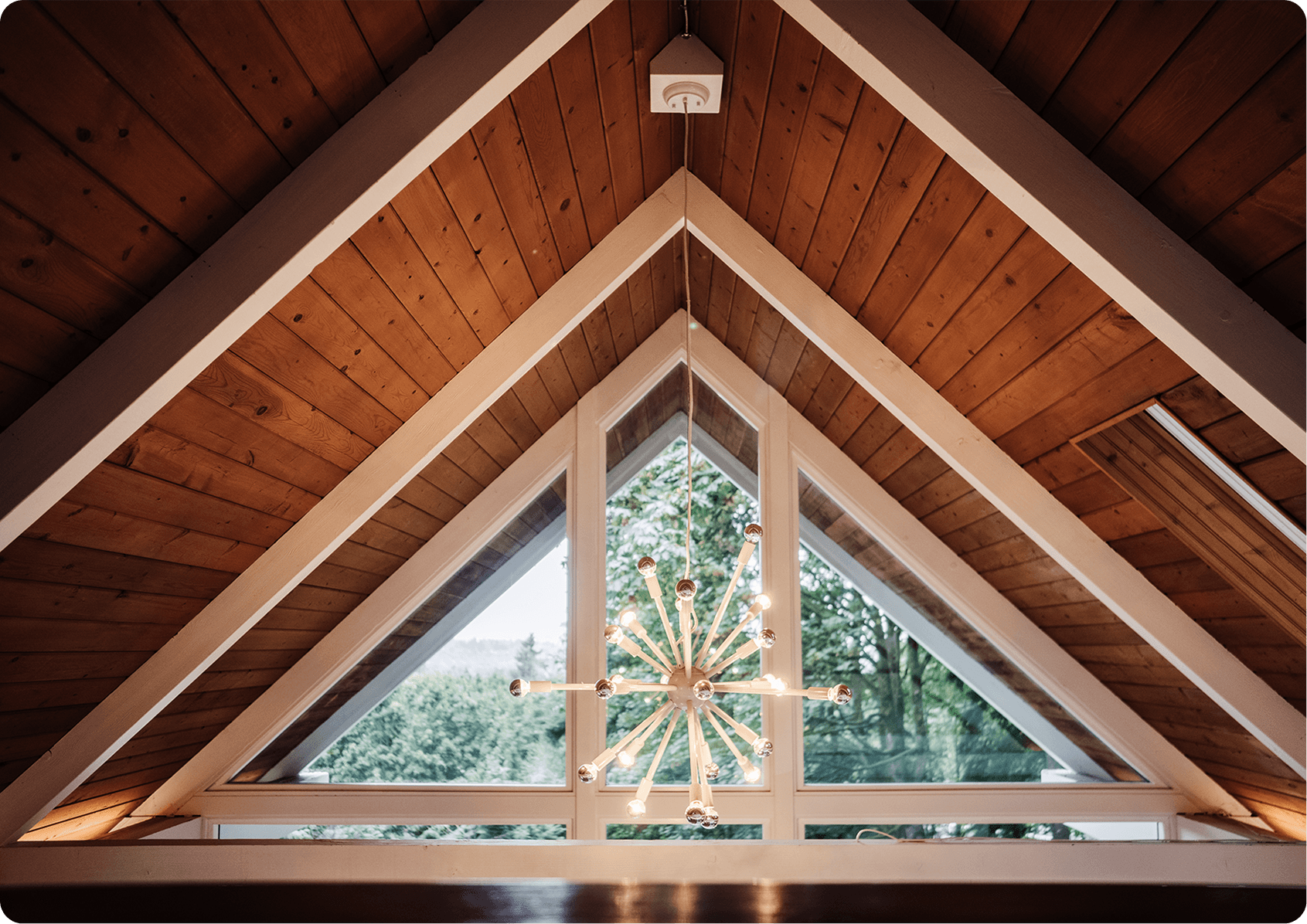Modern bathroom with geometric patterned floor tile, white freestanding tub, brass fixtures, and white shutters