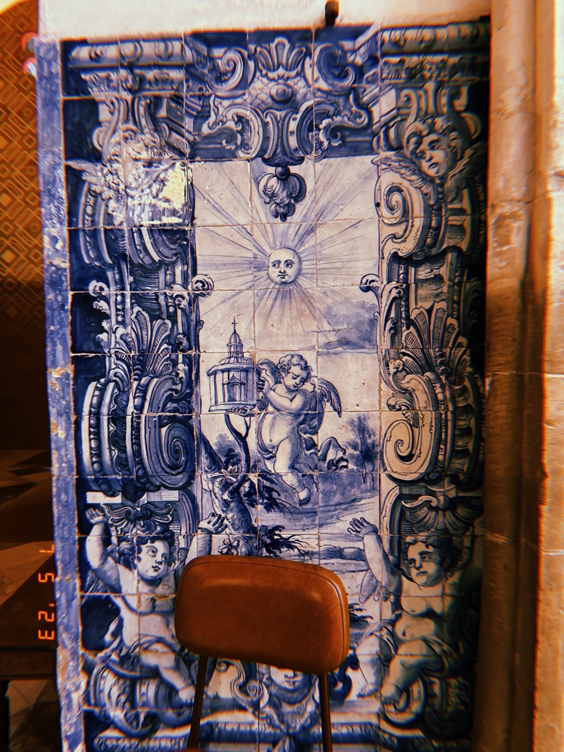 A brown chair interrupts blue-and-white tiles with a sun at the center.