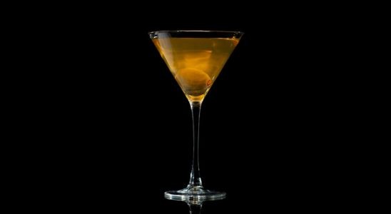 A closeup of a Savory, Year Round Dirty Martini drink against a dark background.